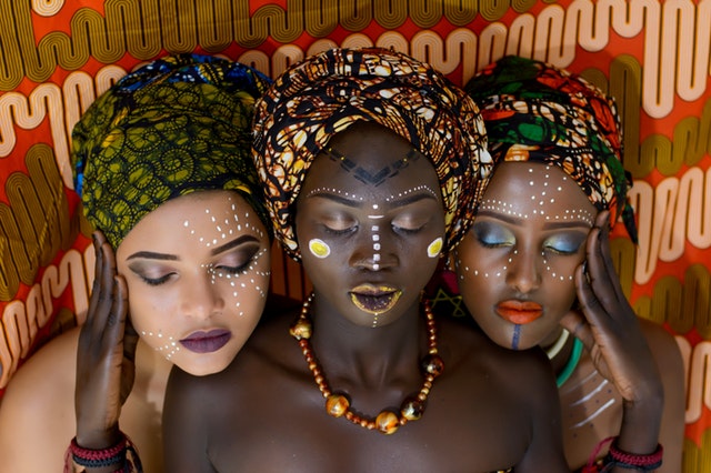 Tri ženy s pomaľovanými tvárami a výraznými šperkami 